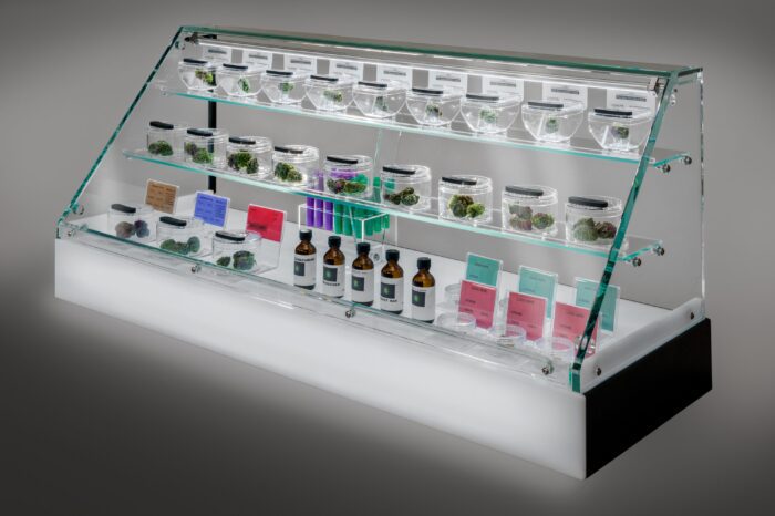 Bud Bar Cabinet™ featuring illuminated display shelves, cannabis flower samples, and strain information cards showcased at cannabis trade shows.