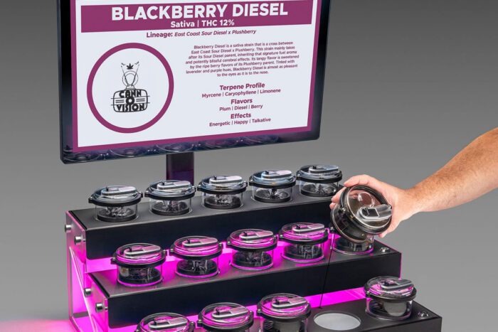 Cann-O-Vision™ lift-and-learn cannabis display with illuminated Canna-Pods® and touchscreen strain information at a trade show demonstration.
